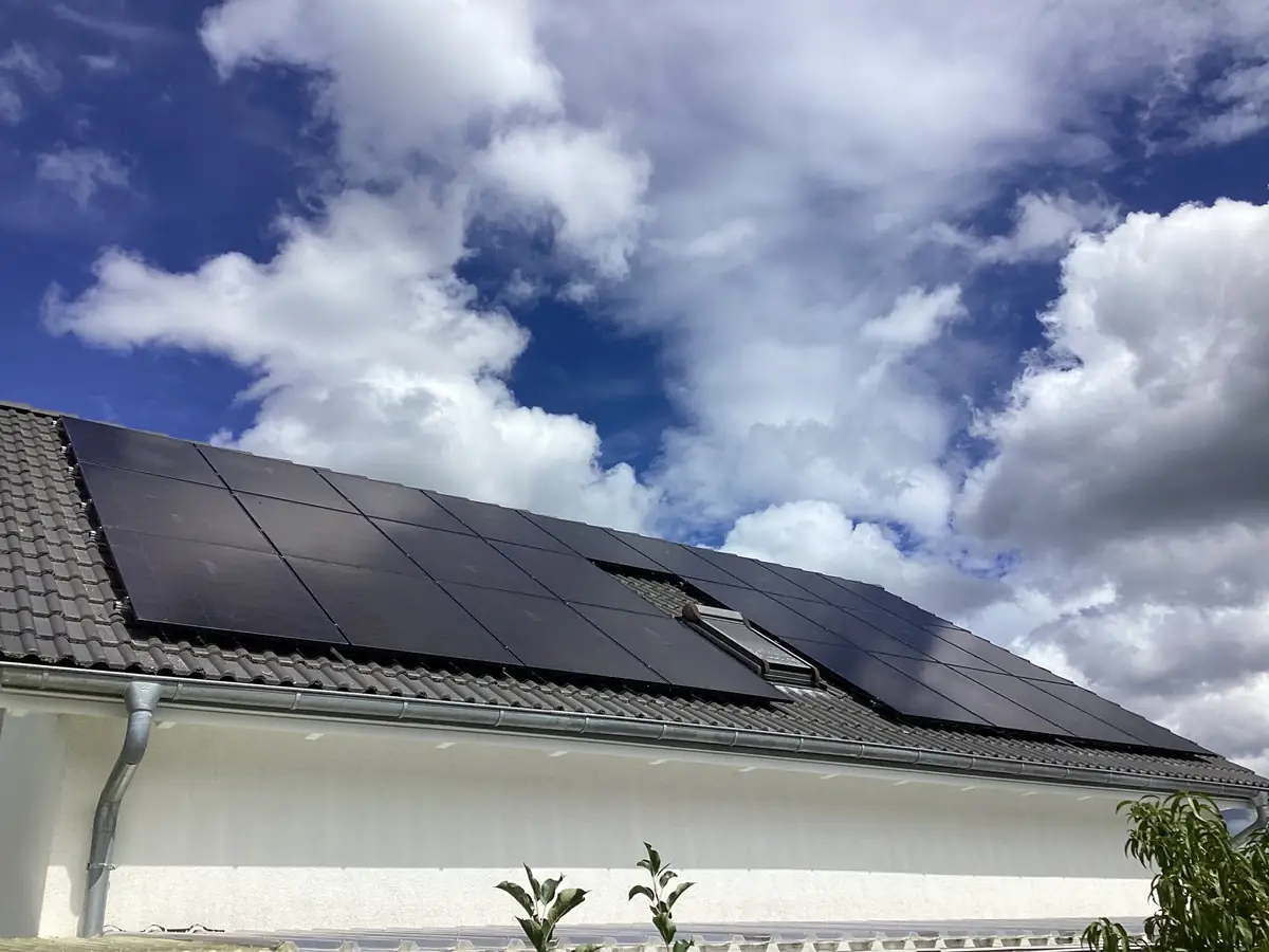 Einfamilienhaus mit Voll-PV-Dach unter dramatischem Himmel