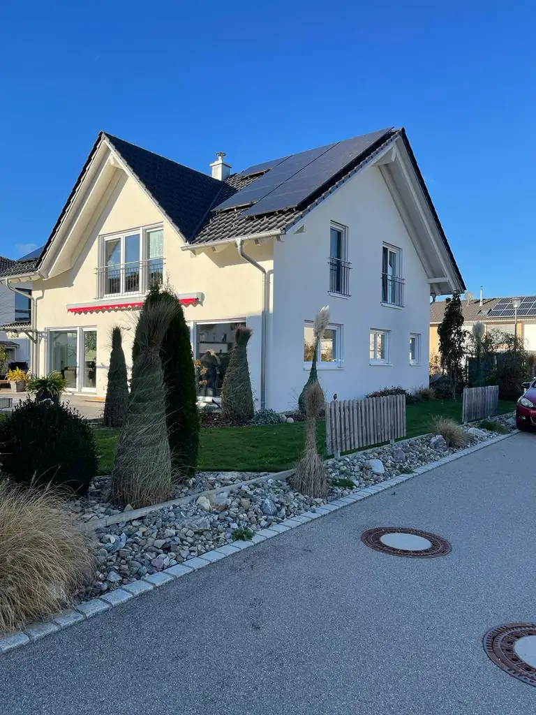 Weißes Einfamilienhaus mit Photovoltaik im Abendlicht