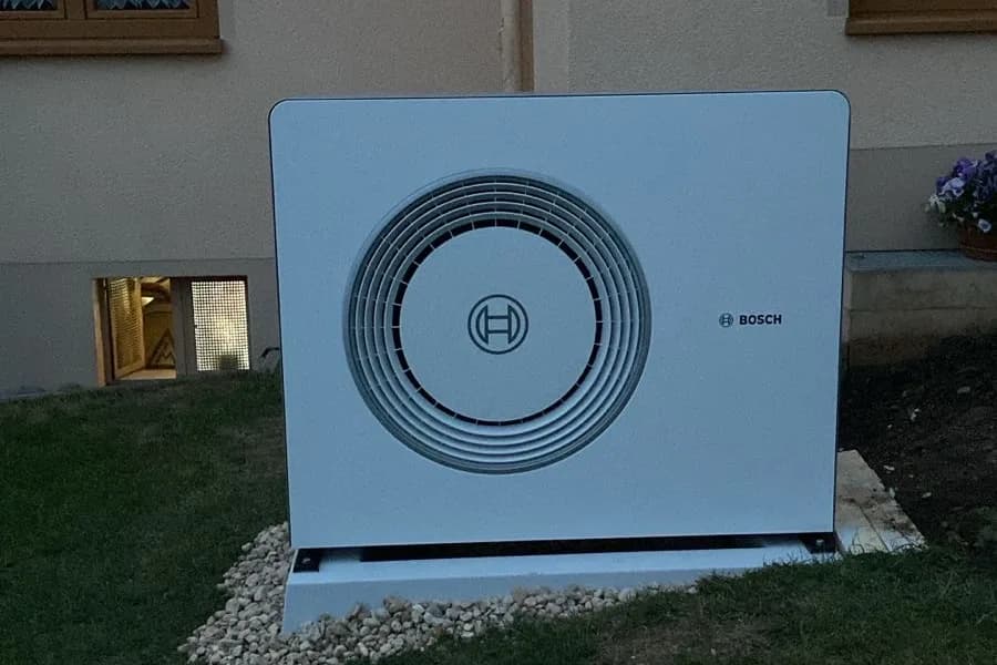 Wärmepumpe auf Kiesbett vor einem Einfamilienhaus